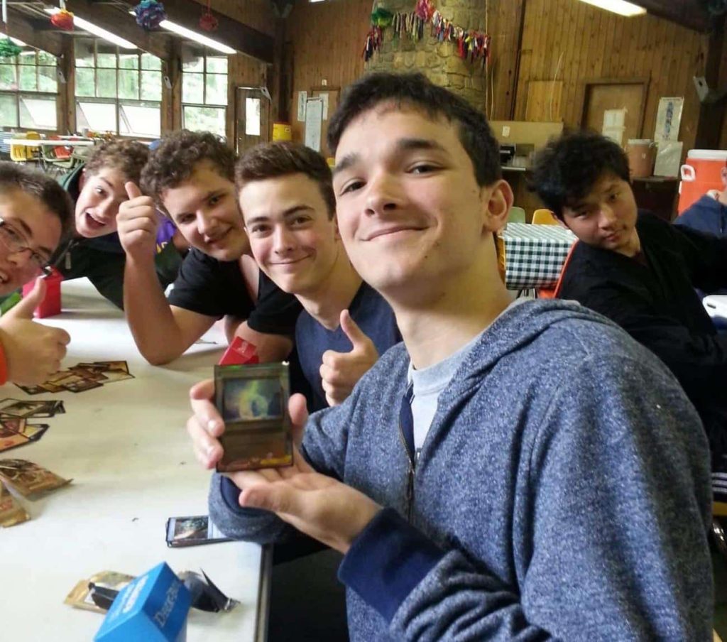 6 young men at Odyssey Teen Camp showing off a rare card from a booster pack at Odyssey Teen Camp.