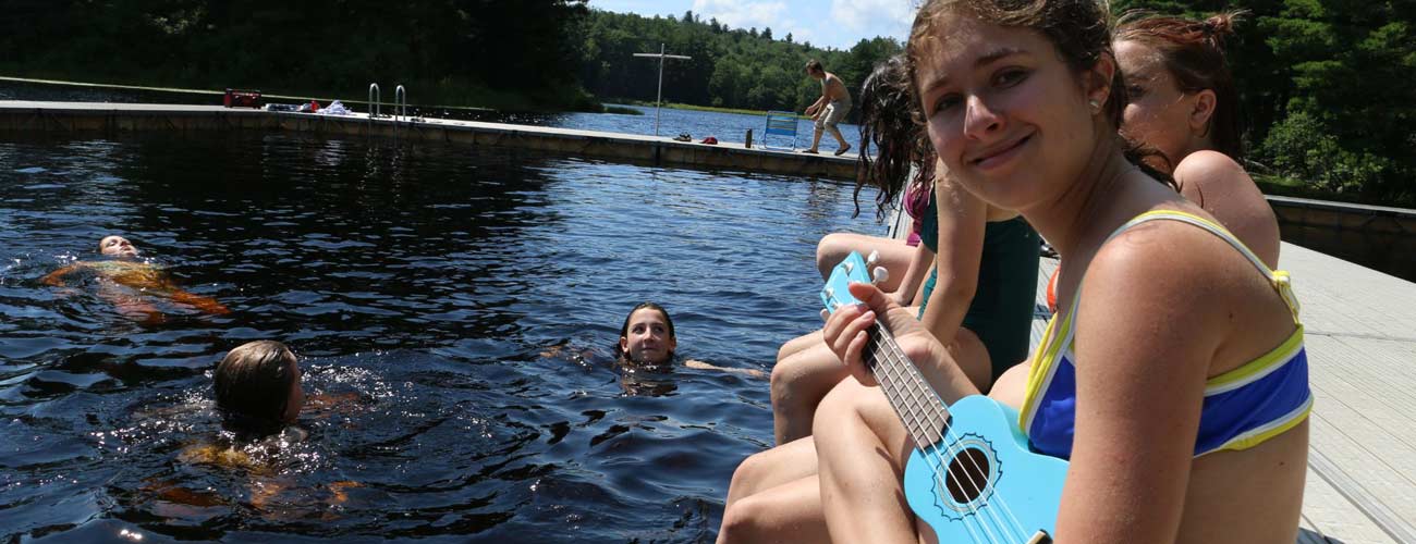 Campers swimming and playing music at the lake