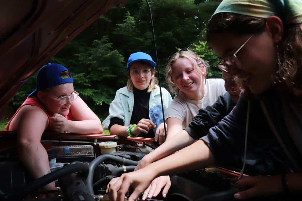 Teen campers working on a car with an instructor