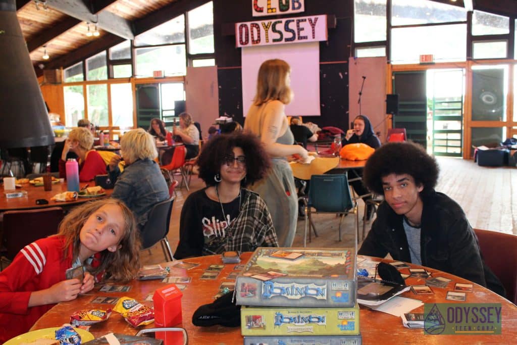 Three campers at the gaming table. One makes a silly face.