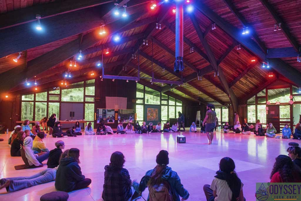 Campers assembled in the recreation room in a giant circle with low light