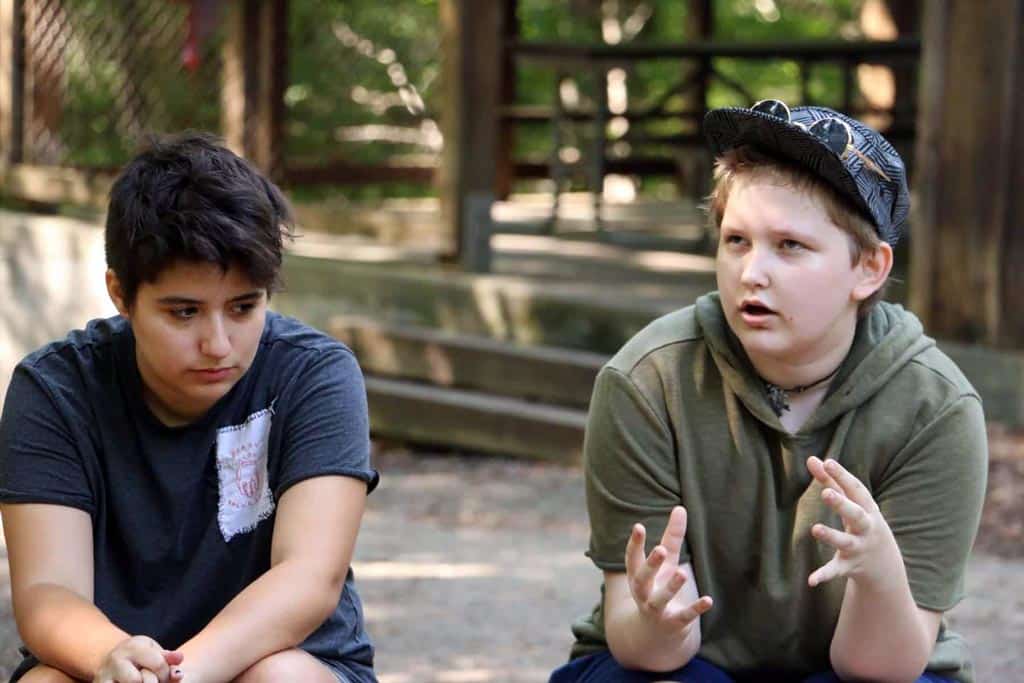 Two teens, one is sharing a concept with hand gestures, the other listens