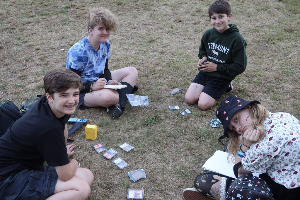 Teens playing Magic: The Gathering on the lawn.