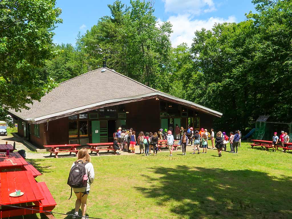 Exterior of dining hall with teens lined up outside waiting for lunch.