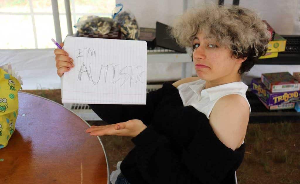Teen holds sign in humorous way that says "i'm autistic."