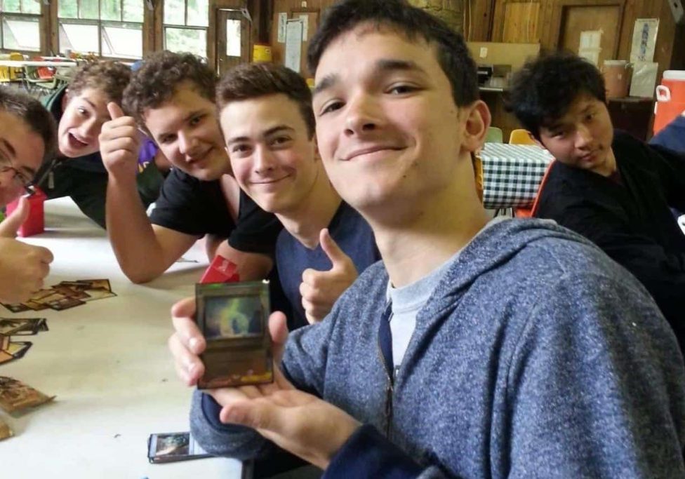 6 young men at Odyssey Teen Camp showing off a rare card from a booster pack at Odyssey Teen Camp.