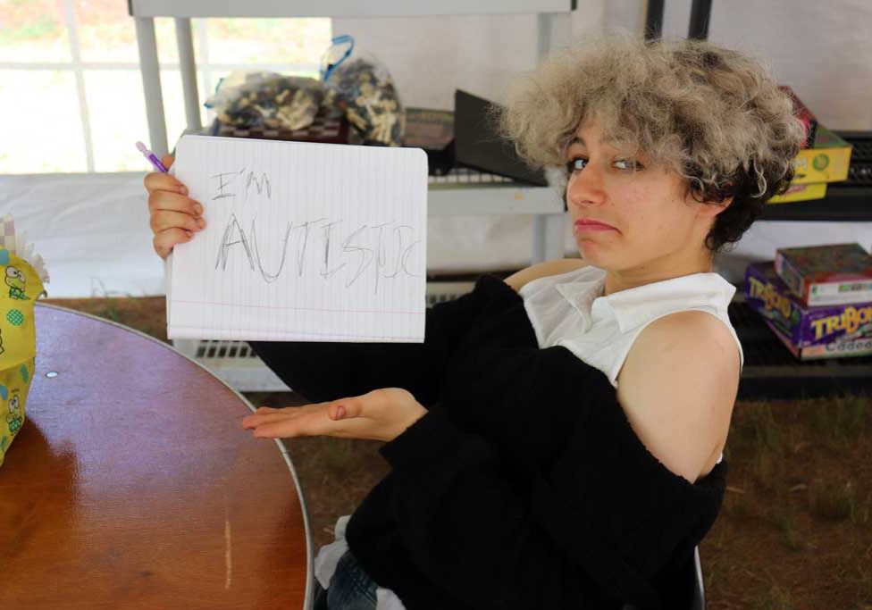 Teen holds sign in humorous way that says "i'm autistic."